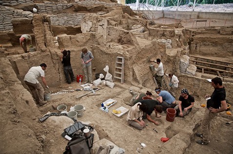 Archaeological dig with people at an excavation site.
